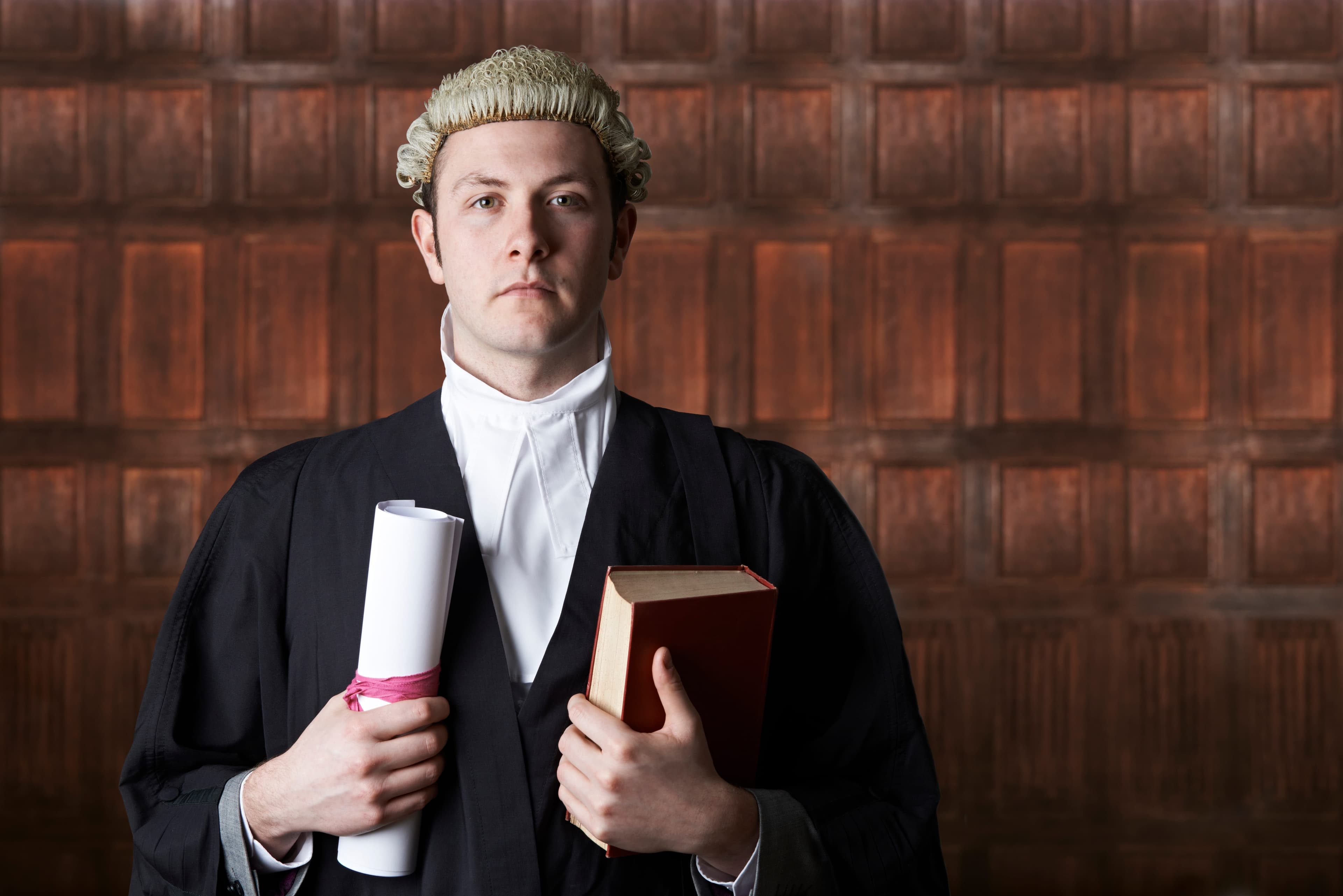 British barrister in formal robes holding a scroll and law book
